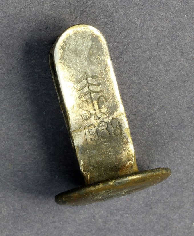 A brass rivet marked S C and dated 1939. Note the pine tree insignia used by the manufacturer Schmöle und Company, Menden.