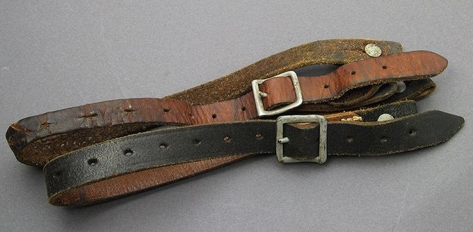 The rear chinstrap is an early example (dated 1938) with brown leather and aluminum buckle. The chinstrap in front (dated 1941) has black colored leather and a painted steel buckle. Notice the wear on the middle part of the early chinstrap. Several years of hard use has resulted in a narrowing of the leather, sweat stains and stress damage.
