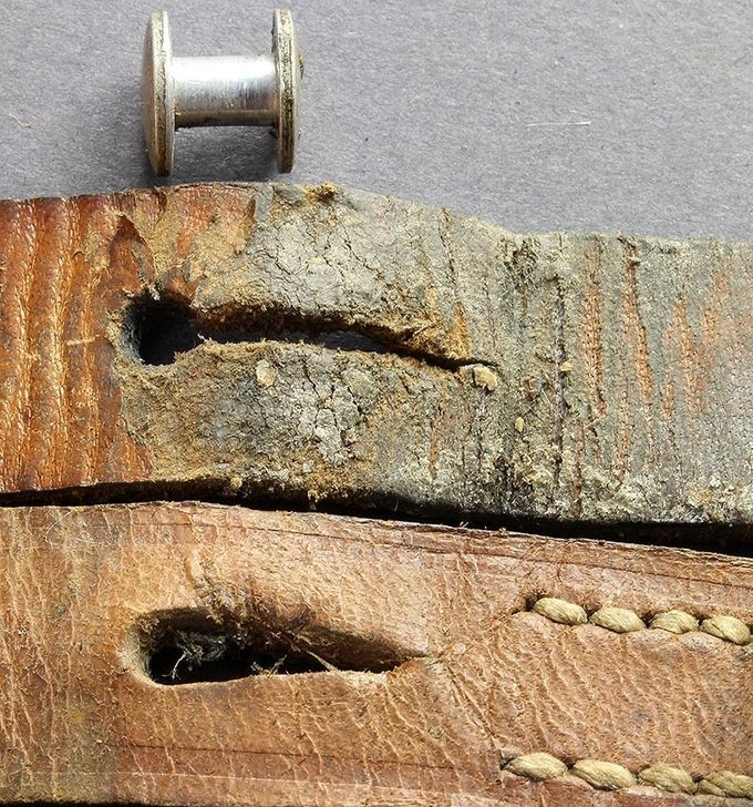 An aluminum stud and two different insertion hole designs. The lower example has a pear-shaped hole which is the most common. Notice the verdigris in the leather on the upper example. 