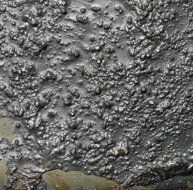 The paint structure of the M35 helmet above. Notice the sand and small pebbles in the paint. The paint has flaked off on the edge revealing the smooth factory M35 paint.