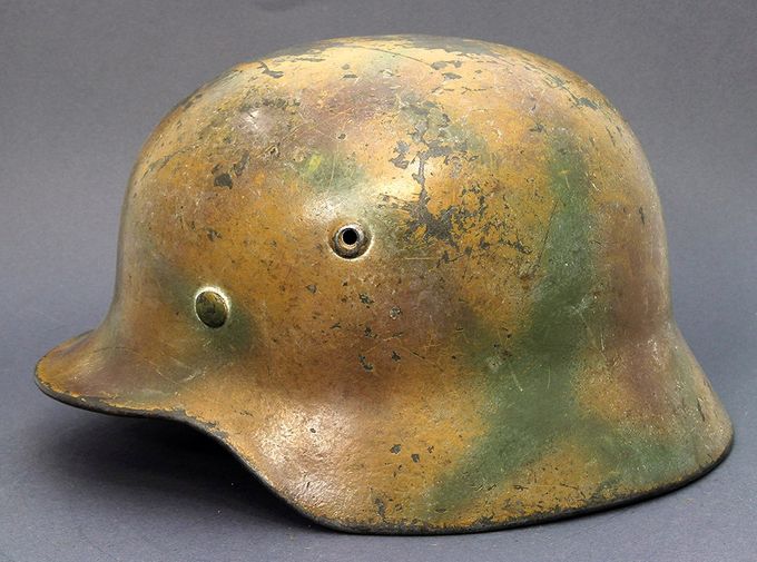 M40 hkp62 spray painted with red, brown and green patterns over a mustard-yellow base. Notice the thin layer of white wash over the whole helmet.