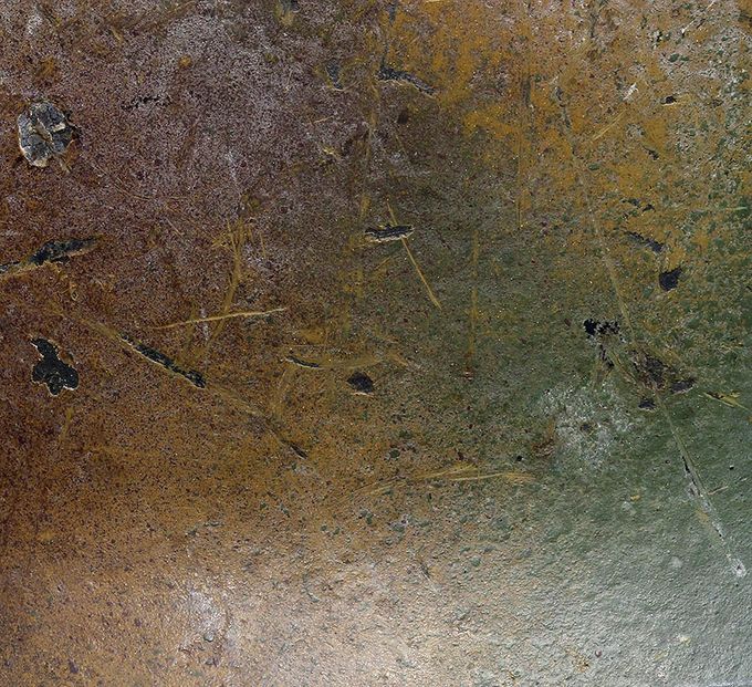 Close-up picture of the surface. Red-brown and green paint on top of the yellow mustard base. Notice the thin layer of whitewash over the paint.