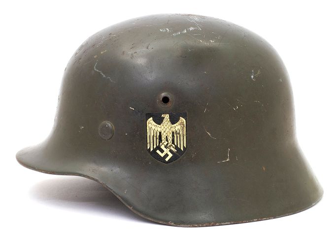 Model 35 (M35) was manufactured from 1935 to 1940 and has a smooth shiny paint which is ranges from bright green to gray-green as shown in the picture above. The generic term for this type of paint is «feldgrau» or field grey. The left side of the M35 helmet features a decal depicting an eagle clutching a swastika. As seen in the photo, the helmet has a vent over the eagle and a rivet placed further down and forward. 